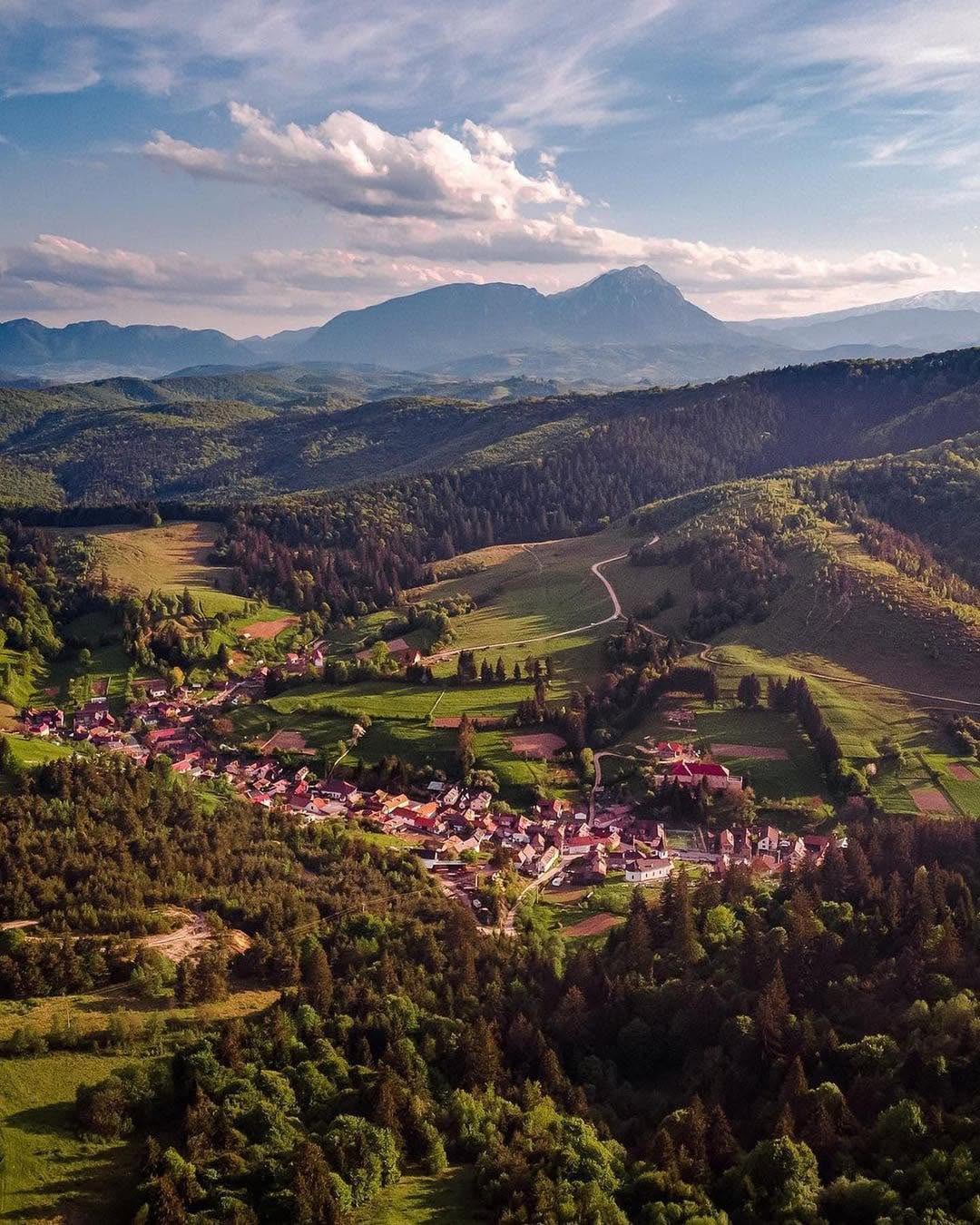 Vedere aeriană asupra comunei Holbav cu Munții Bucegi