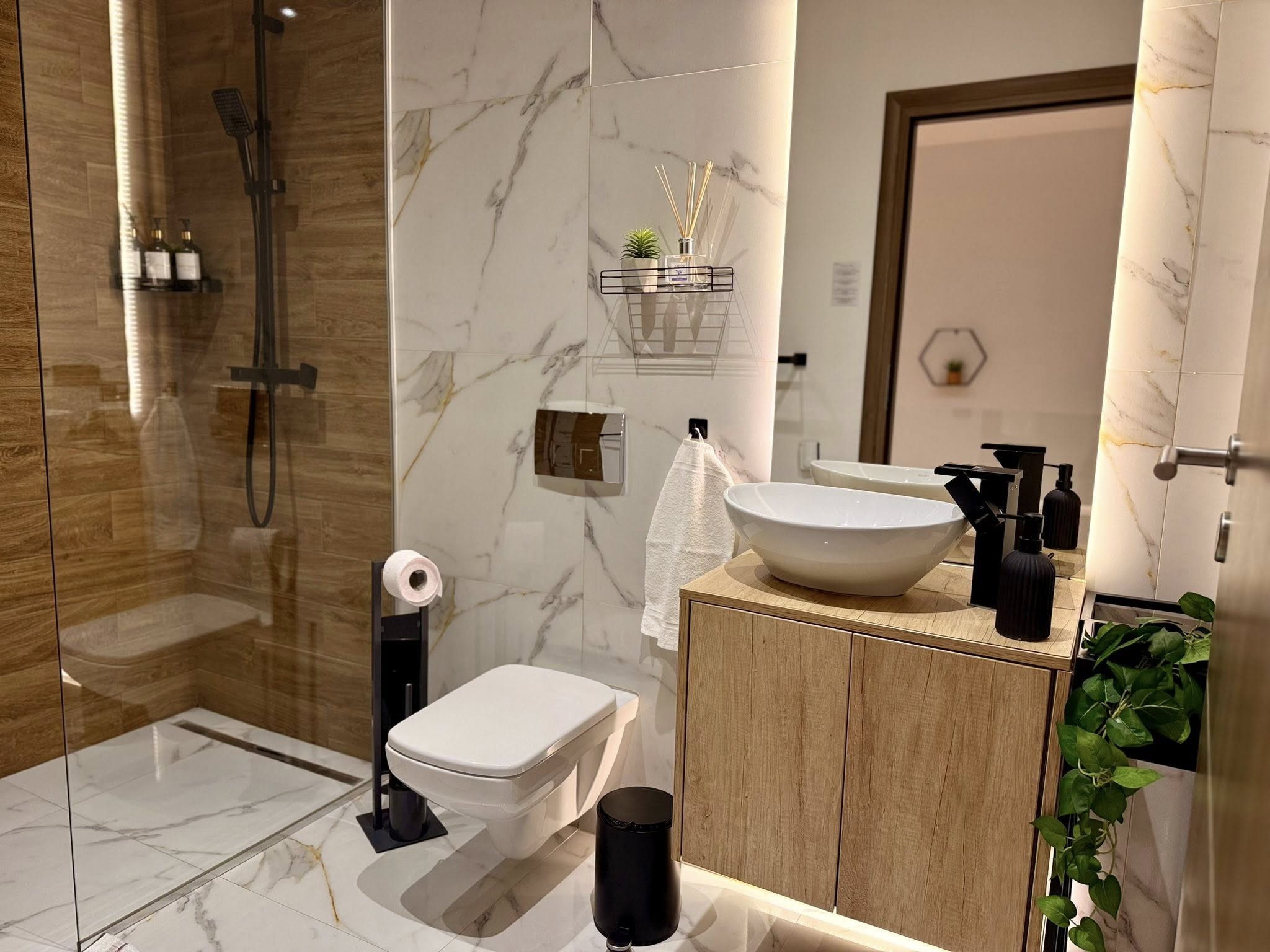 Baie cu marmură, mobilier din lemn și robinete negre